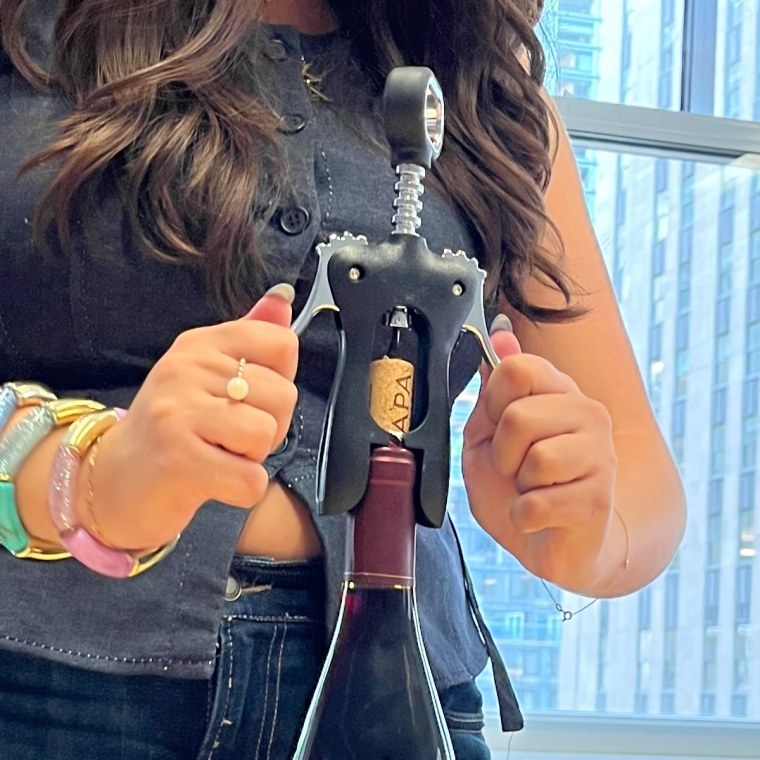 Pushing down the arms of the Houdini wine opener to free the cork from the bottle.