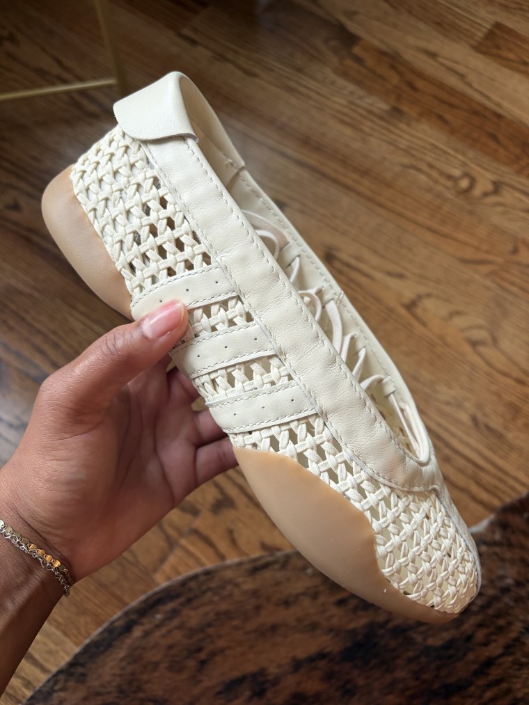  A woman’s hand holding a pair of Adidas Taekwondo Mei shoes
