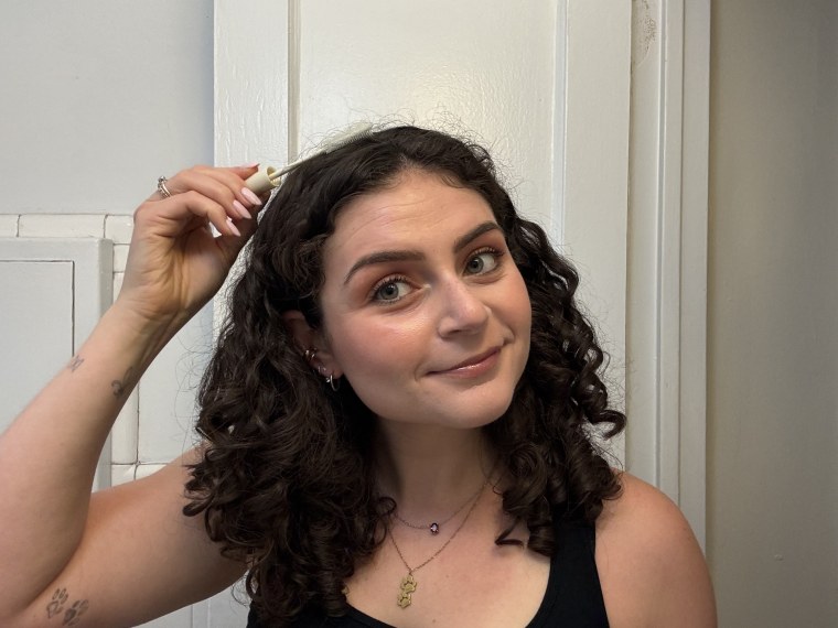 Woman applying taming wand to hair