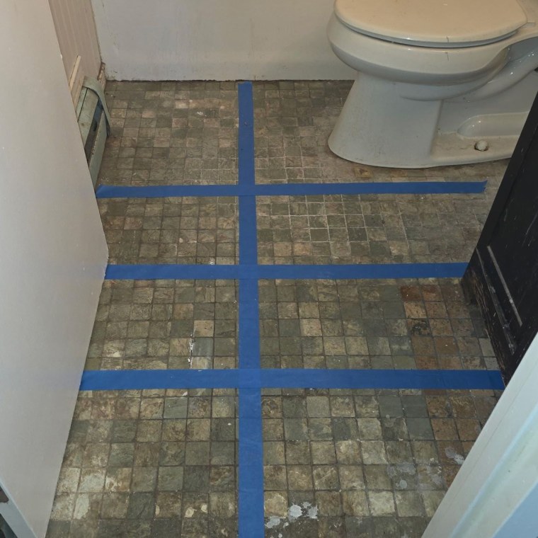 The bathroom floor split into sections with painter's tape before testing began.