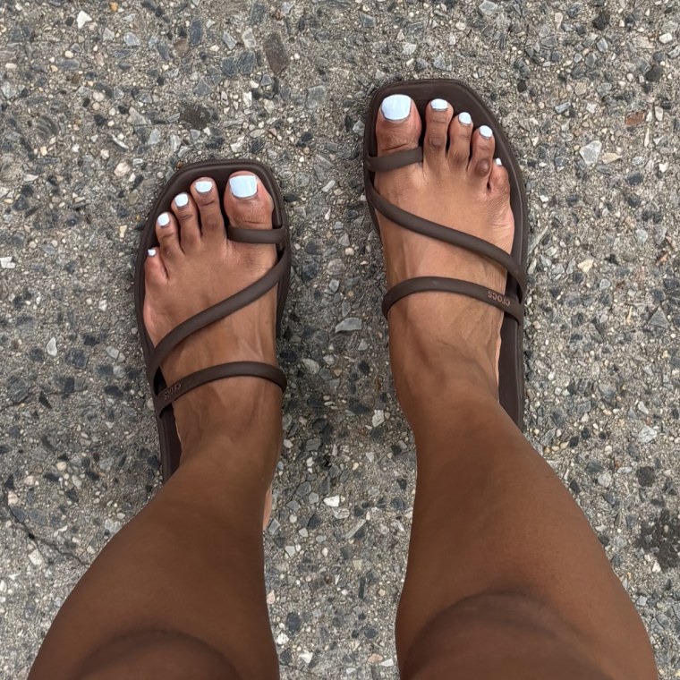 Two feet wearing the Crocs Miami sandals in brown.