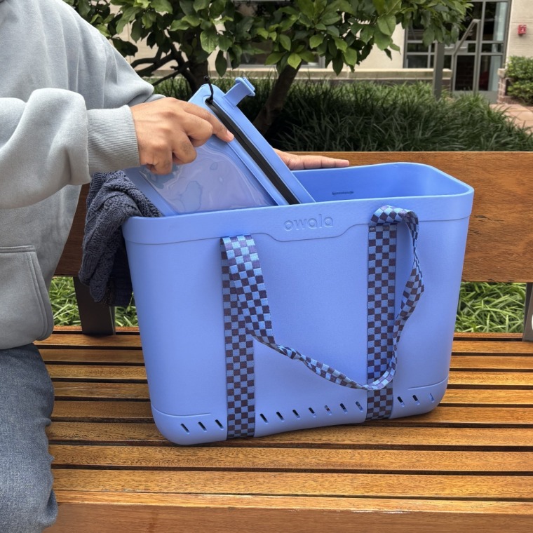 Man in a blue hoodie sitting next to blue Owala Sun-Day Tote