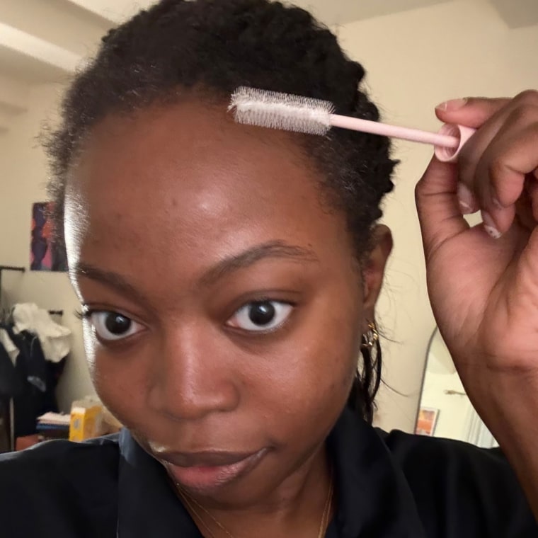 Woman applying taming wand edges of her hair