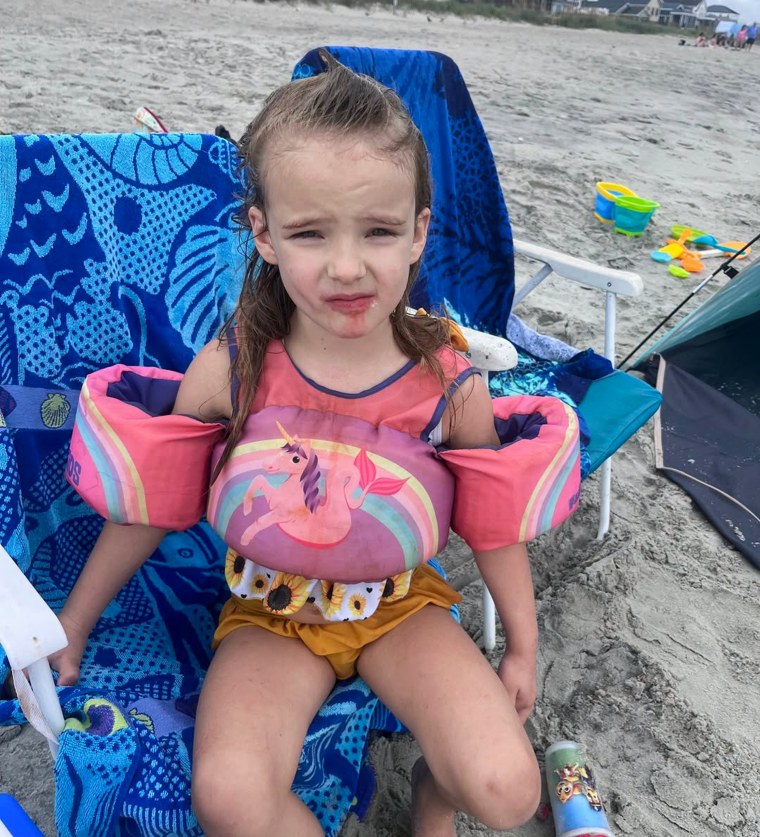 A 5 years-old girl posing for a photo on the beach.