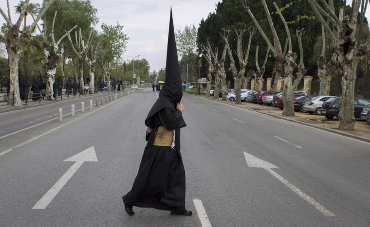 A penitent crosses a street during Holy Week in Seville city in southern Spain on April 3 after the procession he was to participate in was canceled due to rain. In Spain celebrations for Semana Santa, or Holy Week, are often spectacular. Religious statues are carried along on the shoulders of the cofrades, members of the cofradias, lay brotherhoods that organize the processions.