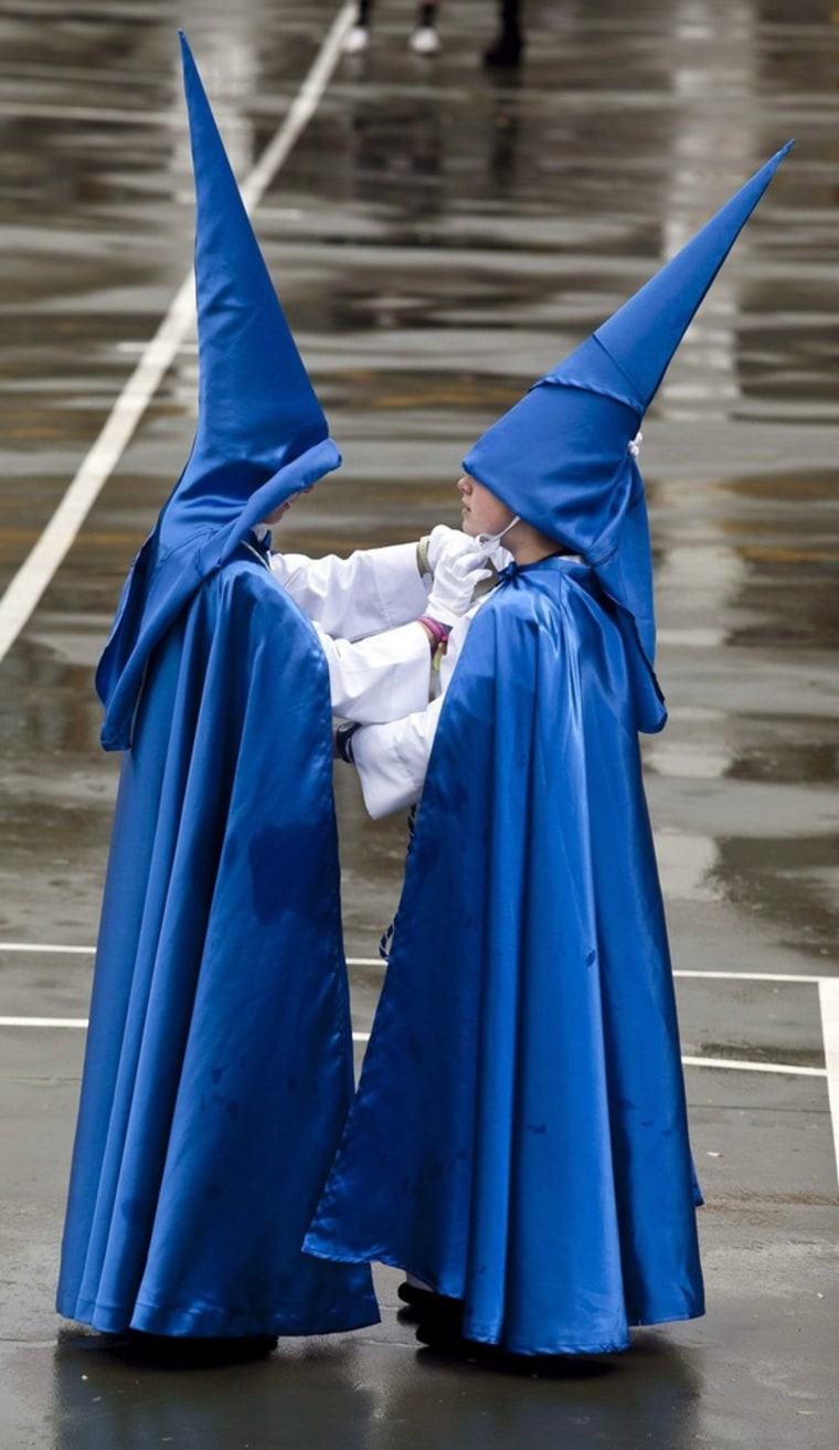 Two penitents in a Holy Week procession help each other take off their hoods in the city of Cordoba in southern Spain on April 3. The procession they were to participate in was called off due to bad weather.