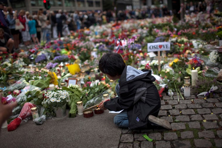 A boy lights a candle to pay tribute to victims of Friday's twin attacks in central Oslo on Monday, July 25.