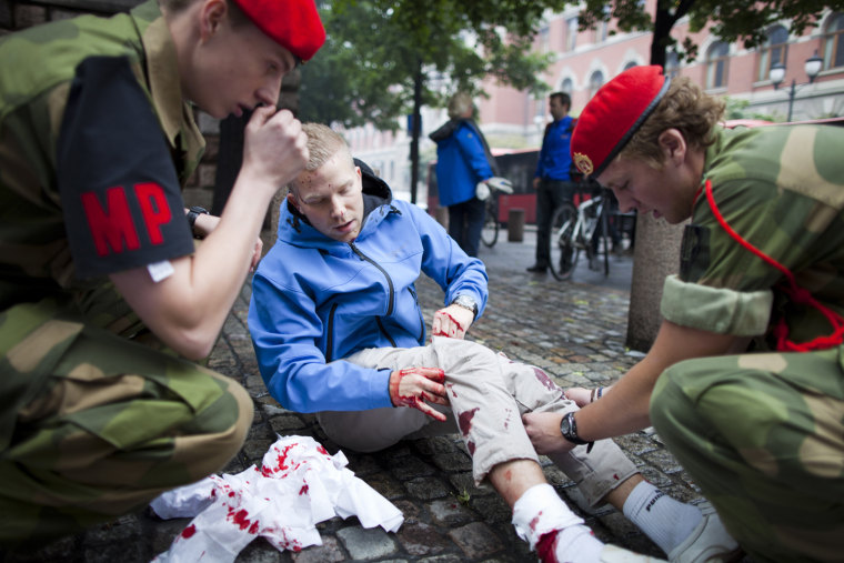 An injured man is treated at the scene after an explosion near the government buildings in Norway's capital Oslo on Friday. At least one person was killed by the powerful explosion which ripped through government and media buildings.