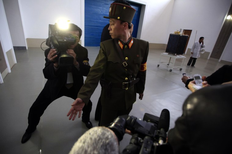 A North Korean soldier tries to keep order as journalists gather around the North Korean satellite.