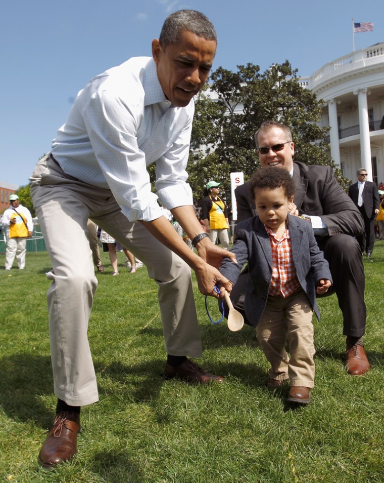 The president helps a young participant roll an egg.