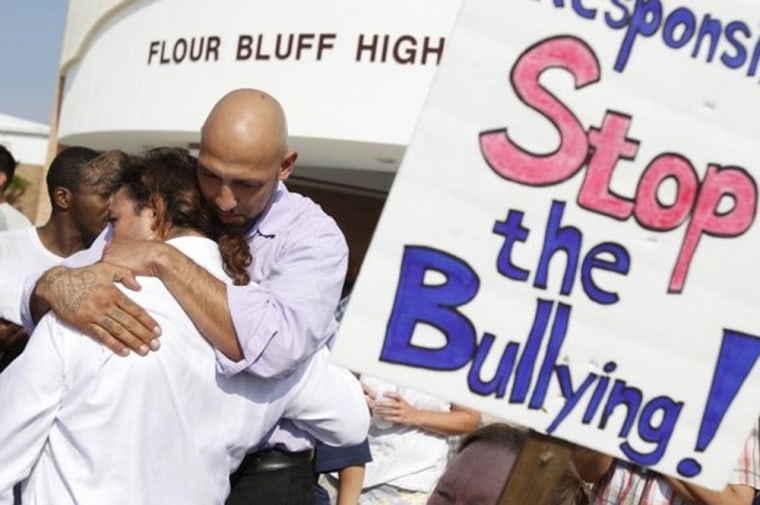 Family friend D. Garcia (right) hugs Mingo Molina, father of Ted Molina, last Wednesday during a rally against bullying outside Flour Bluff High School.