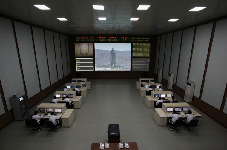 North Korean scientists work as a screen shows the Unha-3 (Milky Way 3) rocket on a launch pad at the West Sea Satellite Launch Site, at the satellite control center of the Korean Committee of Space Technology on the outskirts of Pyongyang April 11, 2012.