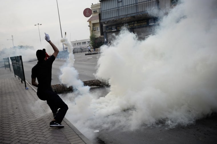 A Bahraini Shiite Muslim throws a tear gas canister fired by riot police during clashes following a demonstration in solidarity with jailed pro-reform activist Abdulhadi al-Khawaja and against the United States' support for the government.