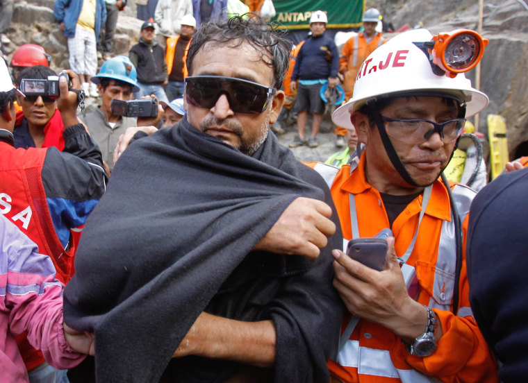An unidentified miner, left, is helped by an emergency worker after being rescued from the Cabeza de Negro gold-and-copper mine in Yauca del Rosario, Peru, Wednesday April 11, 2012. Nine miners had been trapped inside a wildcat mine since April 5. (AP Photo/Martin Mejia)