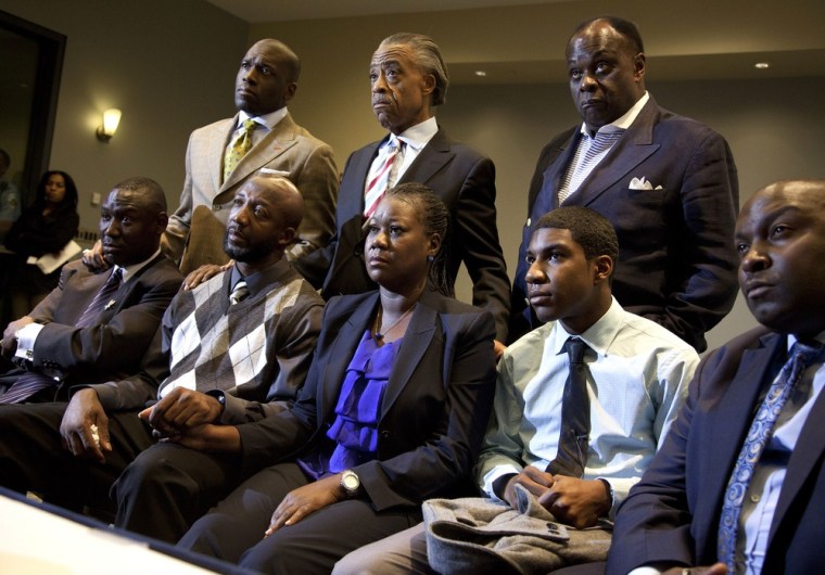 The parents of Trayvon Martin, Tracy Martin (2nd-L) and Sybrina Fulton (3rd-R) hold hands as they watch a news conference on April 11 in Washington D.C. as special prosecutor Angela Corey in Sanford, Florida, announces charges against George Zimmerman.