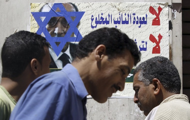 People walk past a poster of presidential candidate and Egypt's former Vice President Omar Suleiman with the Star of David on his face, in Cairo on Thursday. The poster, which was created by the Egyptian Islamic Labour Party, reads,