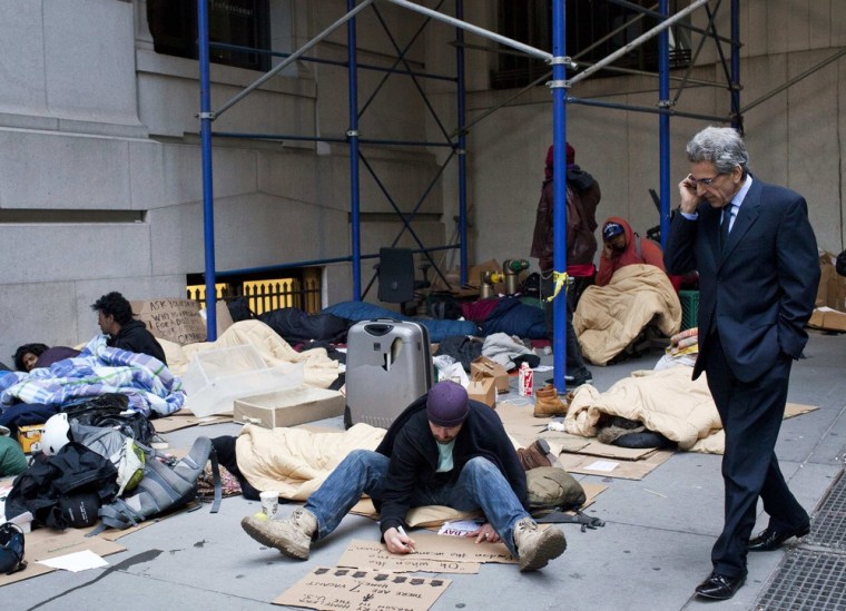 A man walks past Occupy Wall Street protesters at the corner of Wall Street and Nassau Street on April 12. A group of protesters have slept at the corner for the past three nights.