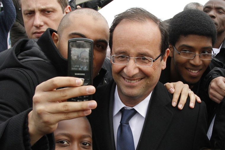 Francois Hollande, Socialist Party candidate for the 2012 French presidential election, poses for a photo with a supporter in Aubervilliers, suburb Paris April 7, 2012.