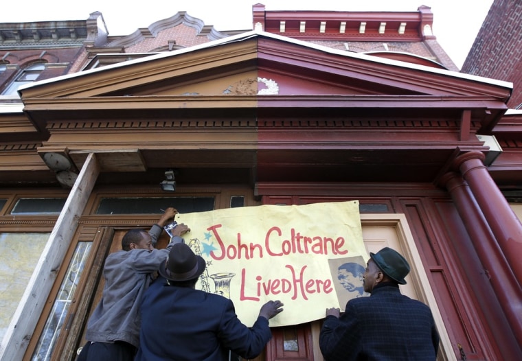 Men hang a banner on the former home of jazz legend John Coltrane on April 13 in Philadelphia.
