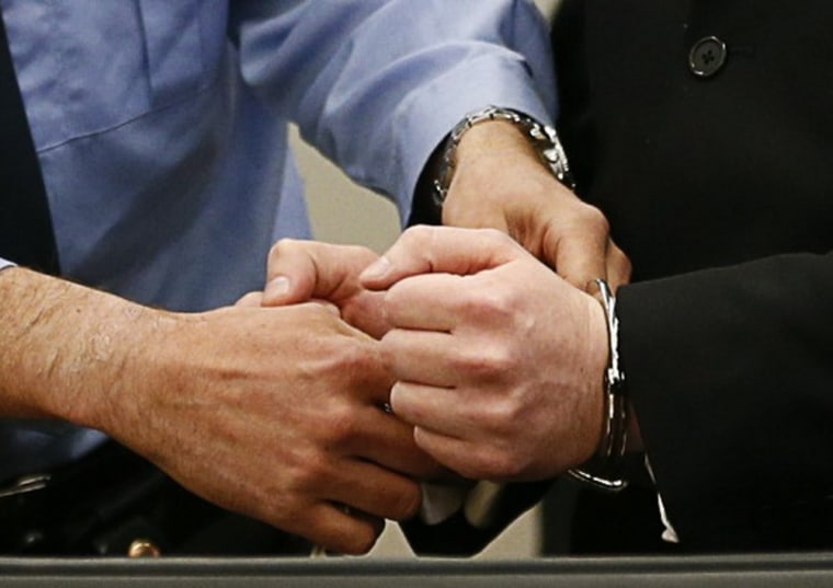 Anders Behring Breivik has his handcuffs removed as he arrives for the first day of his trial.