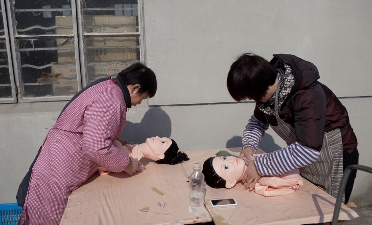 Two women pack finished dolls.