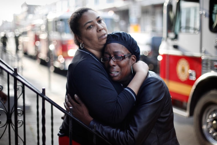 Debra Forrest, right, is consoled in the aftermath of a fire that claimed family members' lives, April 16, in Philadelphia. Officials say the early morning house fire claimed the lives of four people, including two children.