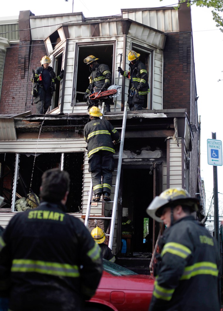 Firefighters work the scene of a deadly row house fire, April 16, in Philadelphia.