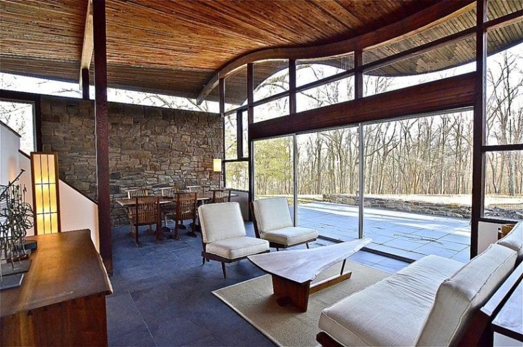 Glass walls stretching to the ceiling look out to the wooded property.