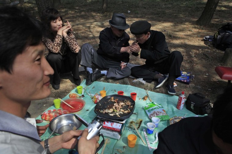 A man lights a cigarette for a friend during a picnic in Pyongyang, North Korea, on April 18, 2012.