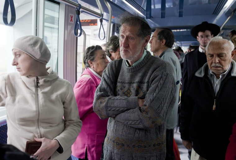 A man's eyes wells up with tears as he and everyone in a car of the electric light tram system comes to a stop in Jerusalem when a siren sounds for two minutes, April 19, 2012, marking Holocaust Martyrs and Heroes Remembrance Day.