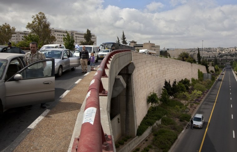 Israelis stand still next to their cars on a highway as a two-minute siren sounds in memory of victims of the Holocaust in Jerusalem on April 19, 2012.