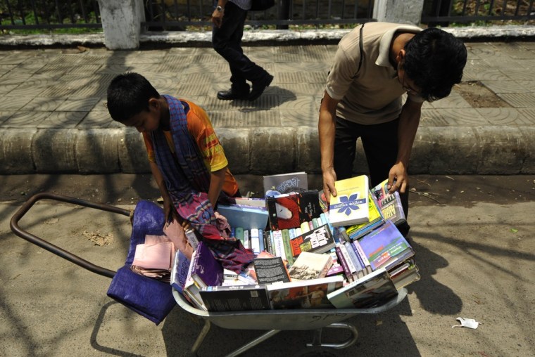 11-year-old Amirul, left, earns 100 taka ($1.22 USD) a day, selling books from a pushcart, as a potential customer browses in Dhaka, Bangladesh on April 19, 2012.