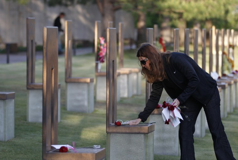 A Housing and Urban Development employee places flowers on the chairs of bombing victims who worked for HUD, in the Field of Chairs at the Oklahoma City National Memorial & Museum before the start of the 17th annual remembrance ceremony in Oklahoma City on April 19.