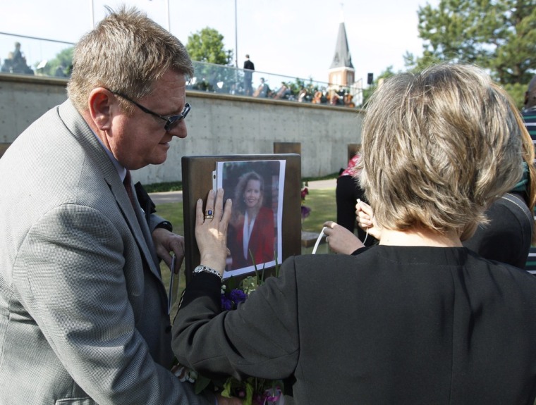 Albert Ashwood, left, and his wife Cindy Ashwood, right, attach a picture of Cindy's sister, Susan Jane Ferrell, to Ferrell's chair in the Field of Chairs at the Oklahoma City National Memorial & Museum, on April 19.