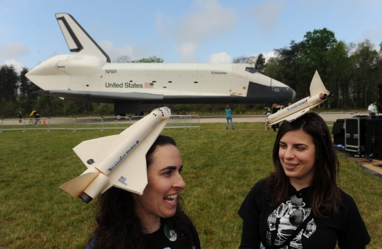 Ashley Koen, left, and Stephanie Harris, right, wear Discovery space shuttle hats while standing in front of the Enterprise space shuttle before a ceremony at Smithsonian National Air and Space Museum's Steven F. Udvar-Hazy Center in Chantilly, Va. on April 19.