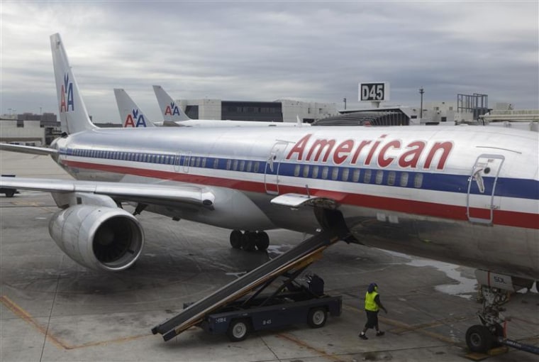 A worker walks underneath an American Airlines airplane at Miami International airport in Miami, Fla.