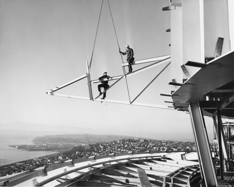 Steelworkers during construction of observation deck level of Space Needle, 1961. This photograph depicts two steelworkers from the Pacific Car and Foundry Company at around the 515 feet level, standing on one of the brackets which will support the Space Needle's observation deck. Remarkably, no men were injured during the often precarious work involved in the construction of the Space Needle.