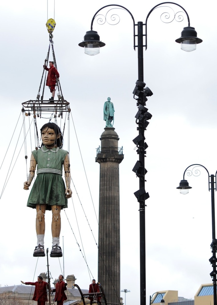 A giant puppett, the neice in the Sea Odyssey story, is lifted from a boat outside St. George's Hall in Liverpool, England on April 20.