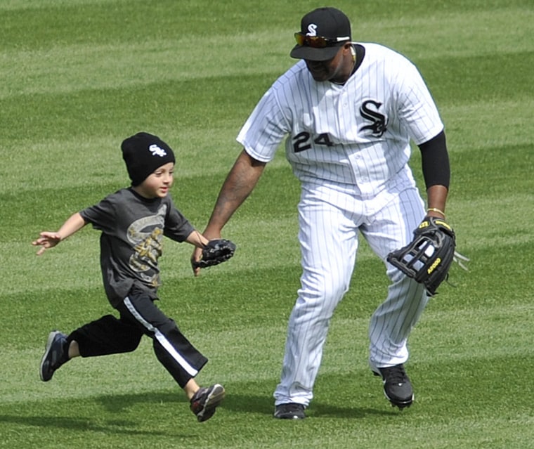 Dayan Viciedo of the Chicago White Sox catches a child running on the field before the start of the seventh inning.