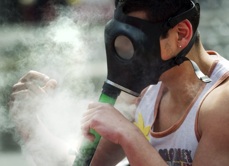 A man takes a hit from a gas mask bong during the annual marijuana 4/20 smoke off at Dundas Square in Toronto, Canada on April 20.