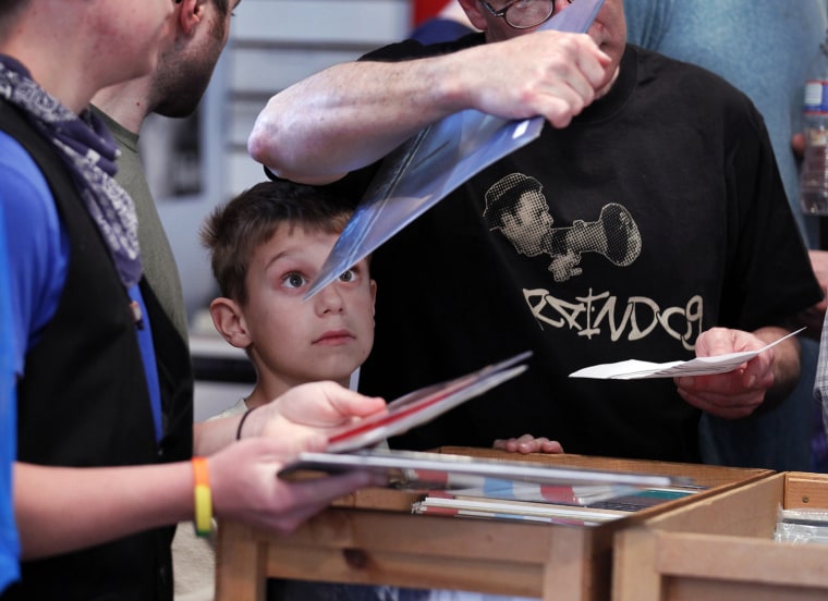 Owen Cooksley, age 8 from Philadelphia, looks at the album in his father's hand on the fifth annual Record Store Day at Main Street Music, April 21, in Philadelphia. On Record Store Day, new and limited edition vinyl records become available for the first time drawing buyers to their local record stores.