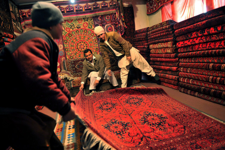 Afghan shopkeeper Ismail Temorzada, 45, center, displays a carpet to customers in his shop on Chicken Street in Kabul, March 3.