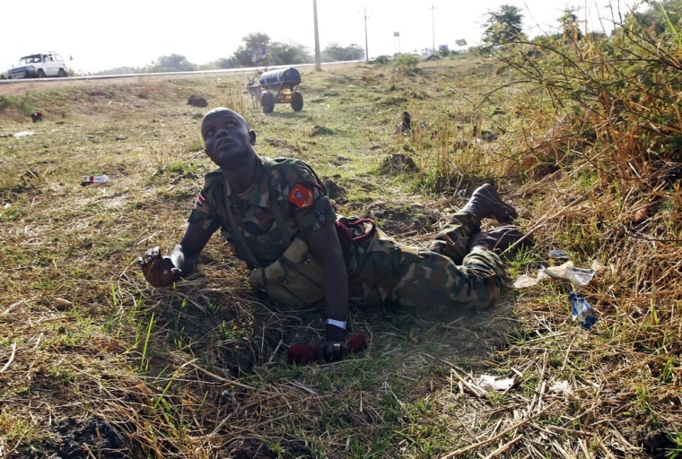 A soldier in South Sudan's SPLA army looks up at warplanes as he lies on the ground to take cover beside a road during an air strike by the Sudanese air force in Rubkona, near Bentiu, South Sudan, on April 23, 2012.