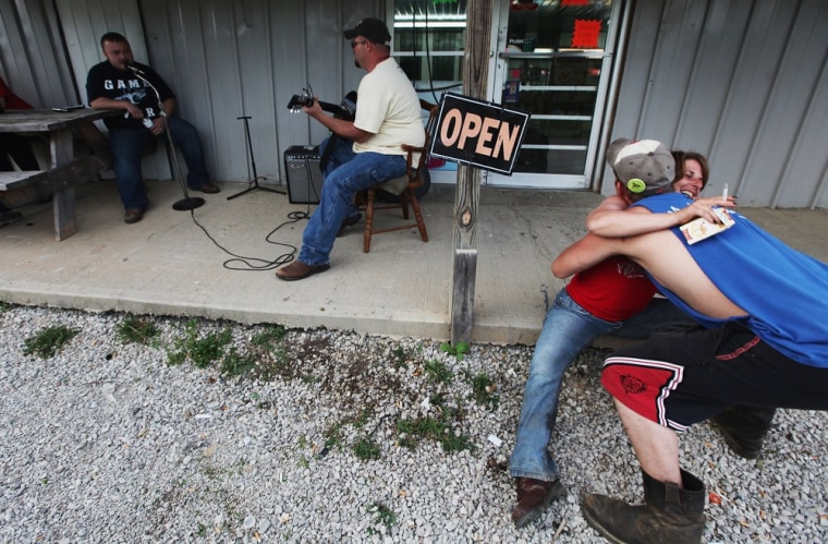 James Moore plays the guitar as Robert Go sings while revelers hug at Joe's Meat Market #2 in Owsley County on April 20 in Booneville, Ky.