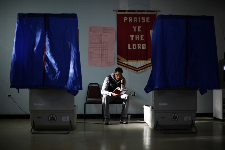 Election worker Khalid Battle reads a book as he waits for voters to cast their ballots in Pennsylvania primary election at Memorial Gospel Crusades Church, Tuesday, April 24, in Philadelphia.