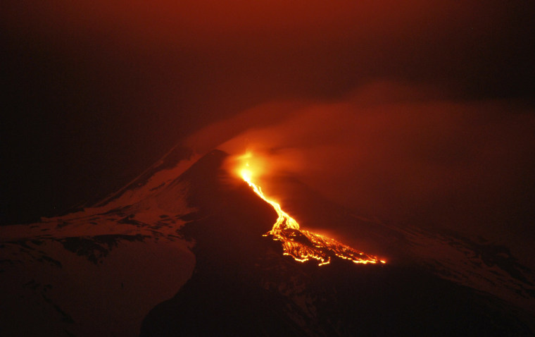 In this photo taken Monday, April 23, lava flows during an eruption of the snow capped Mount Etna volcano, near the Sicilian town of Catania, southern Italy.