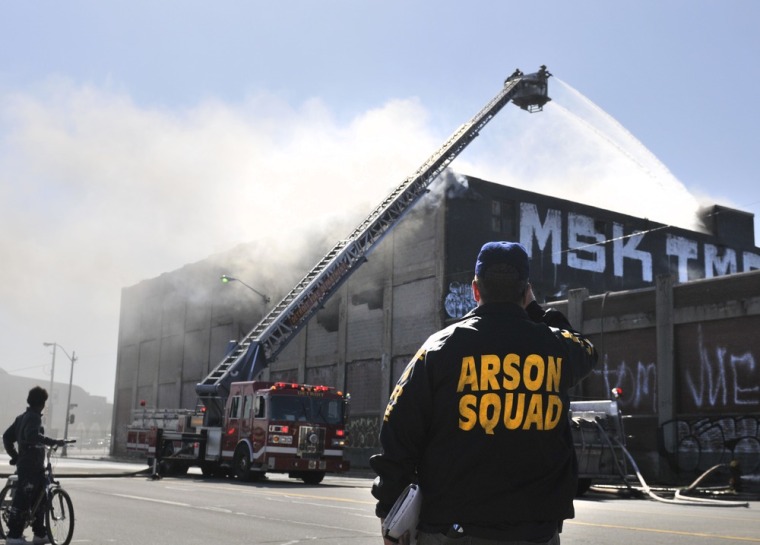 An arson investigator photographs a fire at a Detroit building complex at Sycamore and Grand River on March, 28 2012.