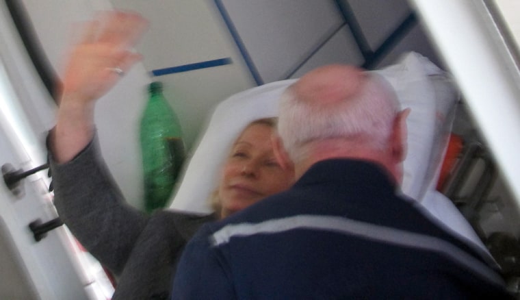 Yulia Tymoshenko waves from a stretcher as she is being carried to an ambulance in on Sunday.