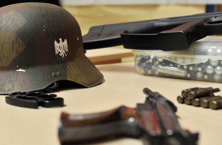 A helmet with a swastika, a pistol, the replica of a rifle and cartridges which have been seized lie on a table during a press conference of the police in Cologne, Germany, Wednesday.