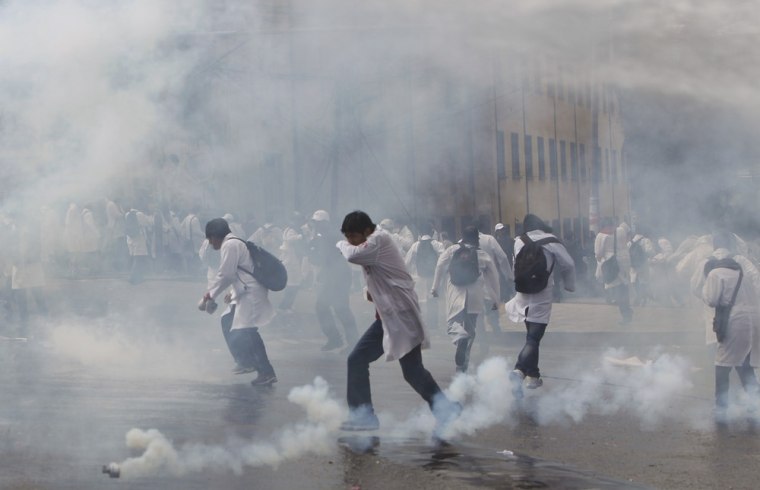 Medical students run from tear gas fired by police as they protest in solidarity with striking public doctors in La Paz, Bolivia on April 24. Public doctors are on their 28th day of an indefinite national strike in response to a decree by President Evo Morales that extends professional working hours from six to eight hours per day.